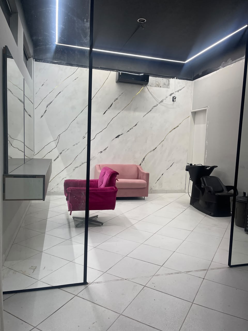 Área de atendimento do Studio Bruna Felix com sofá rosa e parede em mármore
